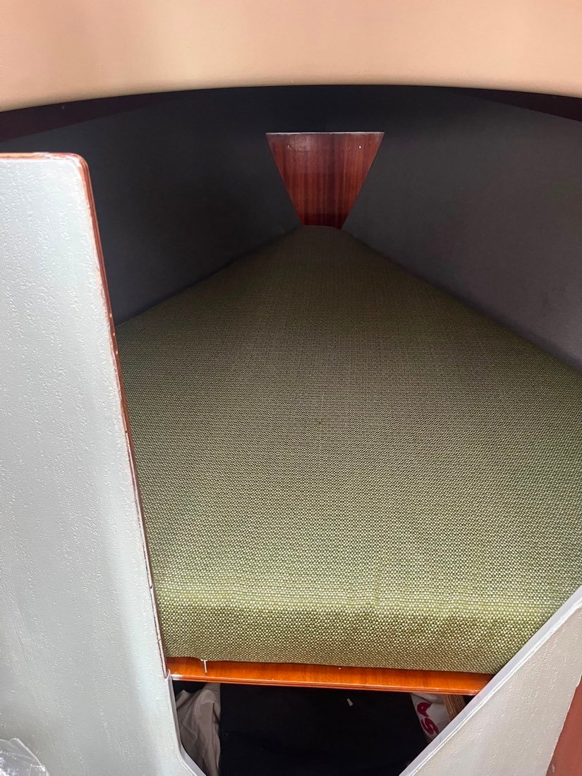 Vooronder van een klassieke zeilboot met een matras in olijfgroene stof